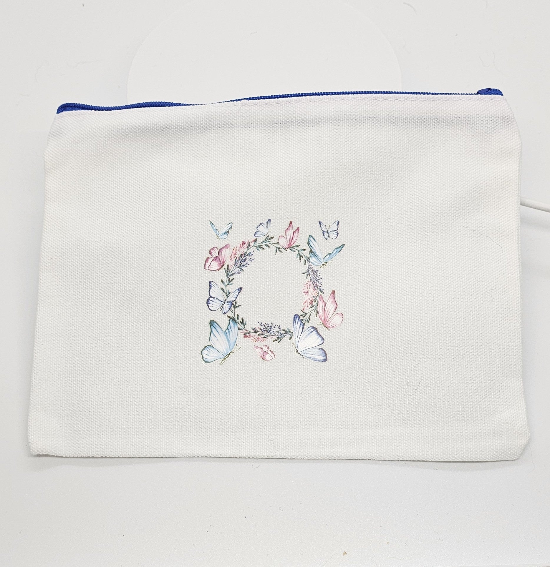 White pouch with floral and butterfly design on a white background