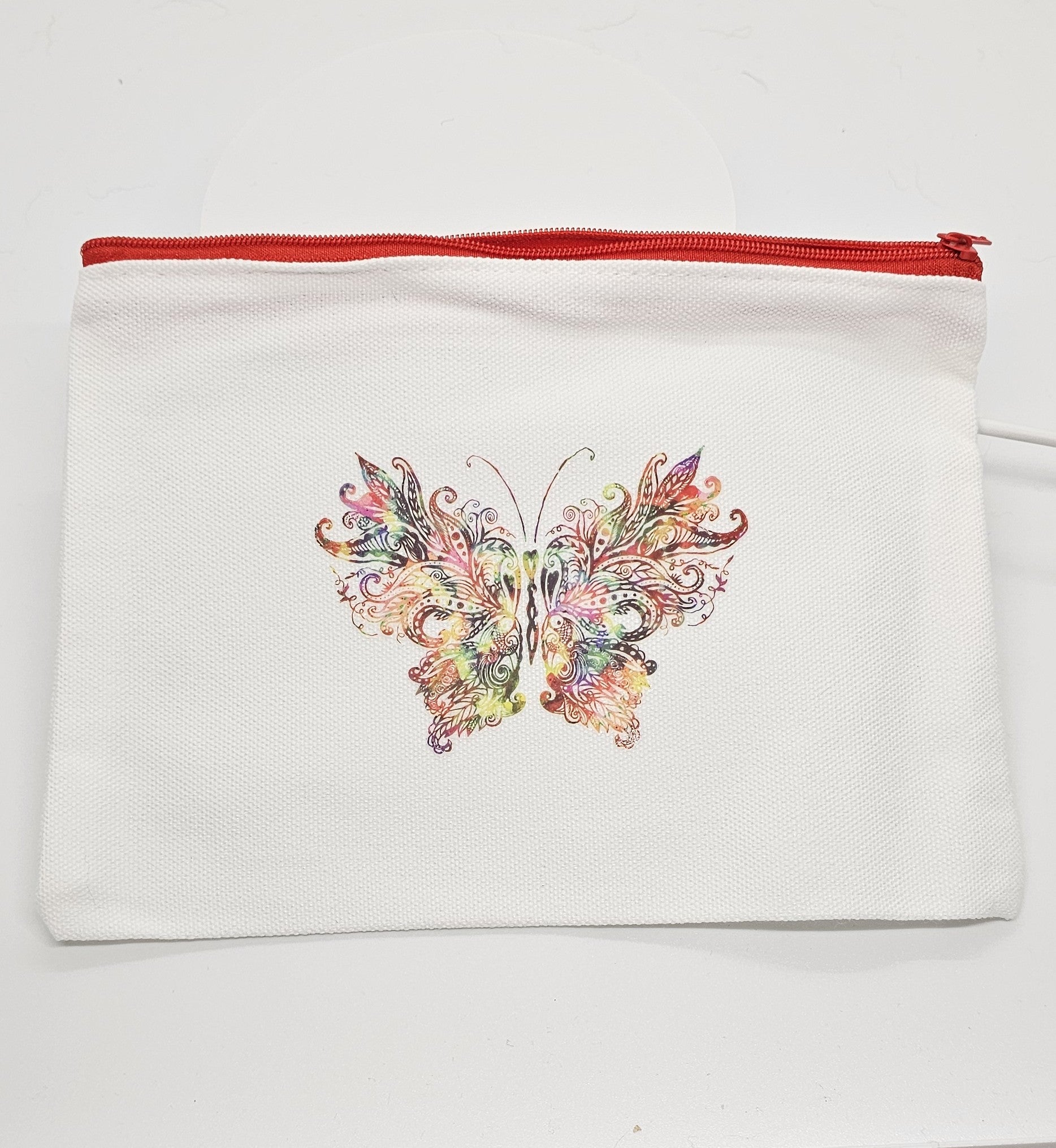 White pouch with a colorful butterfly design and red zipper on a white background
