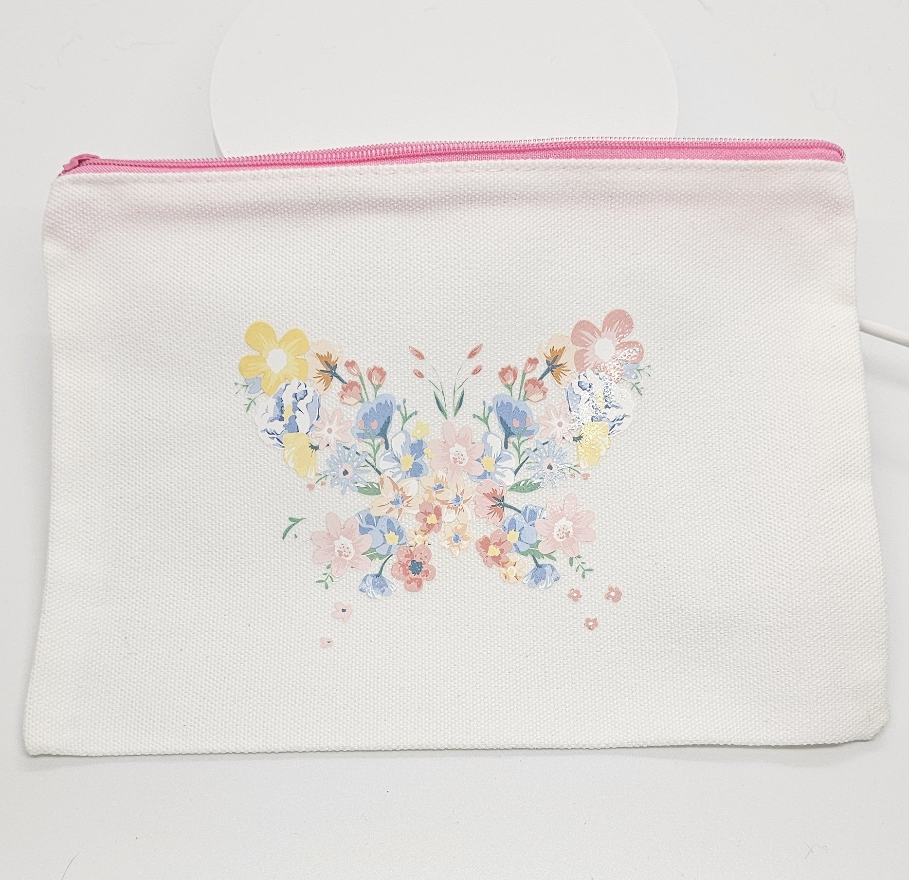 Floral butterfly design on a white pouch with pink zipper.